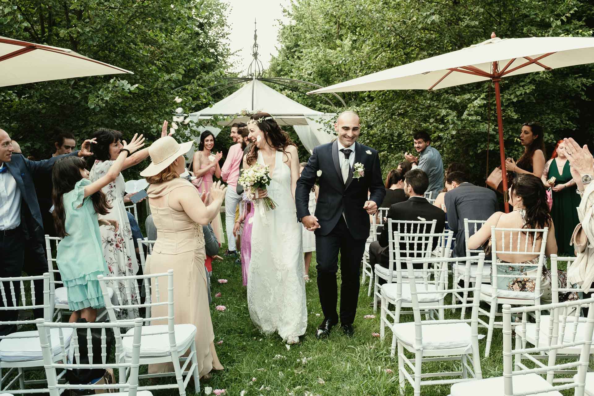 sposi per mano durante l'uscita con lancio dei petali